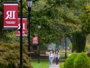 Students walking along campus sidewalk with LR red banners on light posts